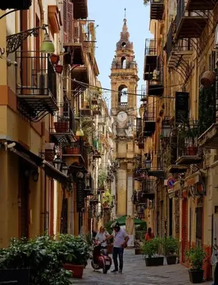a group of people walking down a street with a clock tower at Ai Pupi Siciliani in Palermo