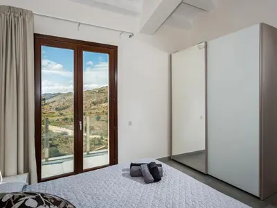 a bedroom with a bed and a large window at Villa Rocchi Livreri by Interhome in Scopello