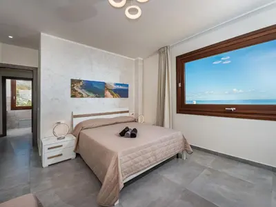 a bedroom with a bed and a large window at Villa Rocchi Livreri by Interhome in Scopello