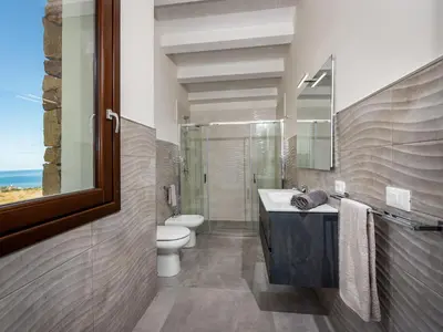 a bathroom with a sink and a toilet and a mirror at Villa Rocchi Livreri by Interhome in Scopello