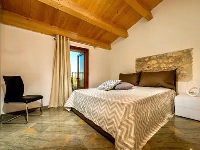 a bedroom with a bed and a chair and a window at Villa Le Muse by Interhome in Scopello
