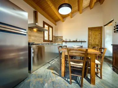 a kitchen with a wooden table and a stainless steel refrigerator at Villa Le Muse by Interhome in Scopello