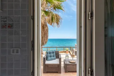 an open door to a patio with the ocean at Villetta Ficarazzi by Wonderful Italy in Ficarazzi
