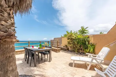 a patio with a table and chairs and the ocean at Villetta Ficarazzi by Wonderful Italy in Ficarazzi