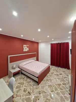 a bedroom with a bed and a red wall at Casa Vera in Piana degli Albanesi