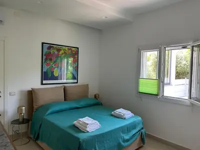 a bedroom with a bed with blue sheets and windows at Villa Lucia in Palermo