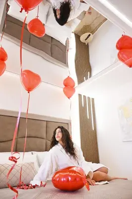 a woman laying on a bed with red balloons at Raquel suite and SPA in Palermo