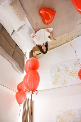 a man laying on a bed with red balloons at Raquel suite and SPA in Palermo
