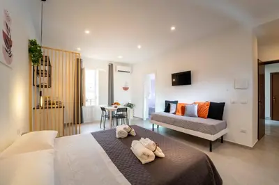 a bedroom with a bed and a couch and a table at MamErì central rooms in Castellammare del Golfo