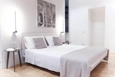 a white bedroom with a large bed and a table at Palazzo Giglio suite in Palermo