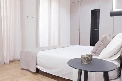a white bedroom with a bed and a table at Palazzo Giglio suite in Palermo