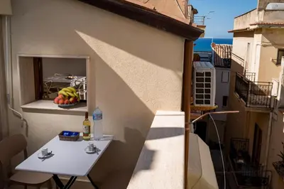 a balcony with a white table and a window at Sofia Rooms in Castellammare del Golfo