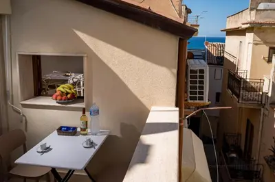a small white table on a balcony with a window at Sofia Rooms in Castellammare del Golfo