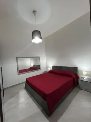a bedroom with a red bed in a white room at Alfa & Omega apartments in Palermo