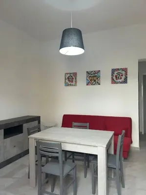 a dining room with a table and a red couch at Alfa & Omega apartments in Palermo