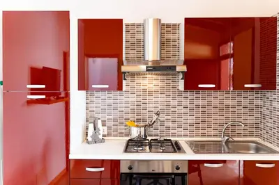 a kitchen with red cabinets and a sink at Terrazza Bellini in Castellammare del Golfo