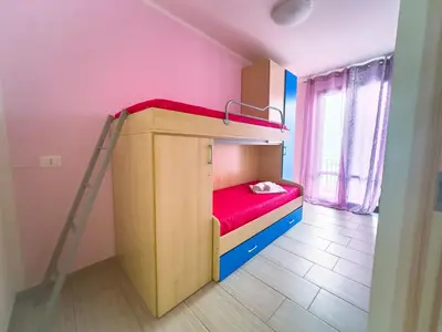 a small bedroom with a bunk bed with red sheets at Terrazza Bellini in Castellammare del Golfo