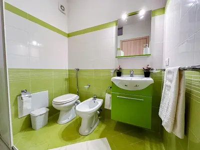 a green and white bathroom with a toilet and a sink at Terrazza Bellini in Castellammare del Golfo