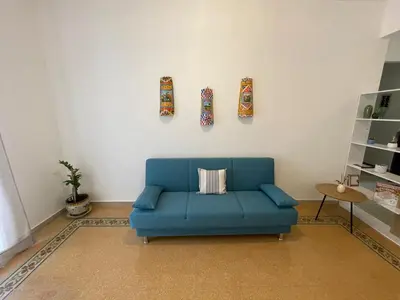 a living room with a blue couch and three pictures on the wall at Casa Marì Holiday House in Palermo