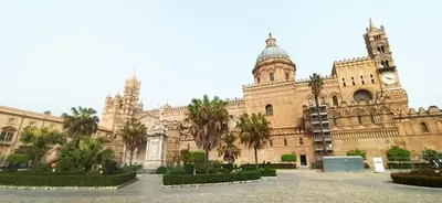 a large building with a clock tower and palm trees at Casa Marì Holiday House in Palermo