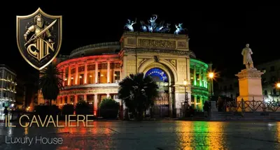 a large building with a clock on it at night at IL Cavaliere in Palermo