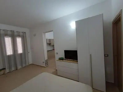 a white living room with a tv and a sliding door at Casa Vacanza Giulia in Castellammare del Golfo