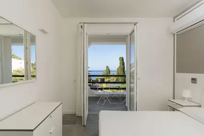 a white bedroom with a view of the ocean at Villa Perla Di Guidaloca in Scopello