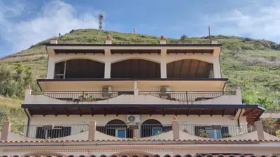 a building with a hill in the background at Costa Azzurra Cefalù Residence in Cefalù