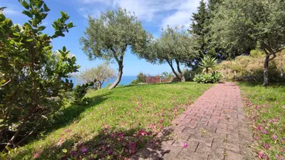 a brick path in a field with trees and flowers at Costa Azzurra Cefalù Residence in Cefalù
