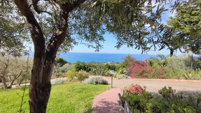 a walkway through a park with the ocean in the background at Costa Azzurra Cefalù Residence in Cefalù