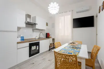 a kitchen with white cabinets and a table with chairs at Orleans Apartment in Palermo