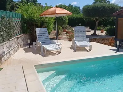 two chairs and an umbrella next to a swimming pool at Castellaccio Scopello Villetta con piscina in Scopello