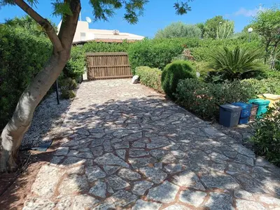 a stone walkway in a garden with a bench at Castellaccio Scopello Villetta con piscina in Scopello