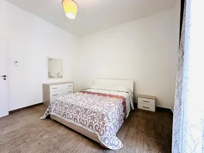 a white bedroom with a bed and two night stands at Billy Home in Villabate