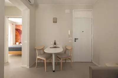a white dining room with a table and two chairs at Le perle del capo in Palermo