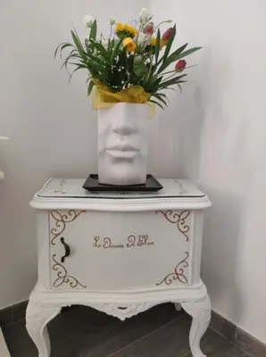 a white table with a vase of flowers on it at La dimora di Elma in Palermo