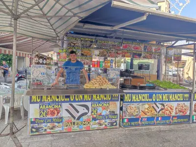 a man standing in front of a food stand at La dimora di Elma in Palermo