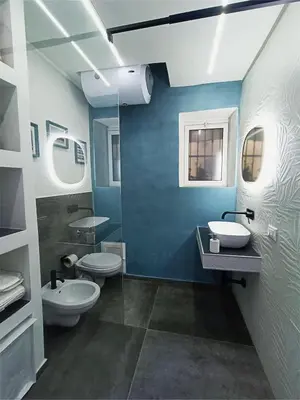 a bathroom with two toilets and a blue wall at Agghiorna&skura 2,0 in Palermo