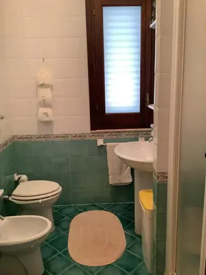a bathroom with two toilets and a sink and a window at Macari House in Macari