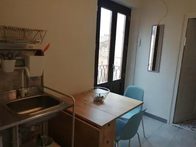 a kitchen with a sink and a table and chairs at Domus Case Vacanze civico del mare in Castellammare del Golfo