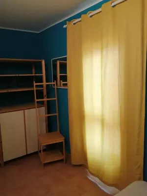 a bedroom with a yellow curtain and a chair at Domus Case Vacanze civico del mare in Castellammare del Golfo