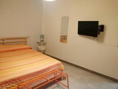 a bedroom with a bed and a tv on the wall at Domus Case Vacanze civico del mare in Castellammare del Golfo