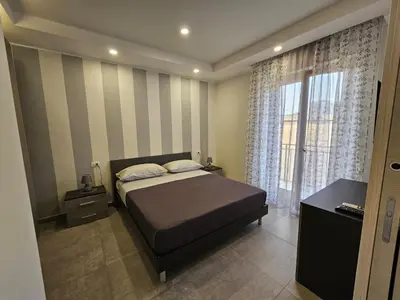 a bedroom with a bed and a large window at Flowers Apartments in Marineo
