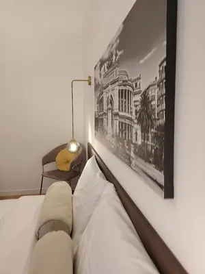 a bedroom with a white bed with a picture on the wall at Casa O'Tama in Palermo