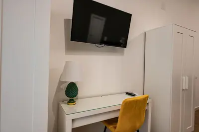 a white desk with a lamp and a tv on a wall at Molinari Palermo in Palermo