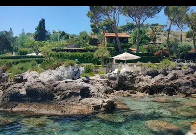 a living room with a stone fireplace and a table and chairs at Alle due Torri, villa sulla roccia a picco sul mare in Altavilla Milicia