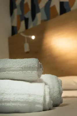 a stack of white towels sitting on a bed at Appartamento completo con parcheggio privato - Villa Ciaculli in Villabate
