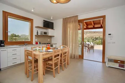 a kitchen with a wooden table and chairs in a kitchen at Villa Ninfa in Castellammare del Golfo