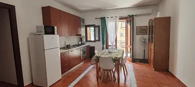 a kitchen with a table and a white refrigerator at Casa Vacanze In Piazza in Terrasini
