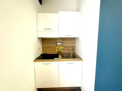 a small kitchen with white cabinets and a sink at Intero Appartamento con Solarium - Villa Ciaculli in Palermo